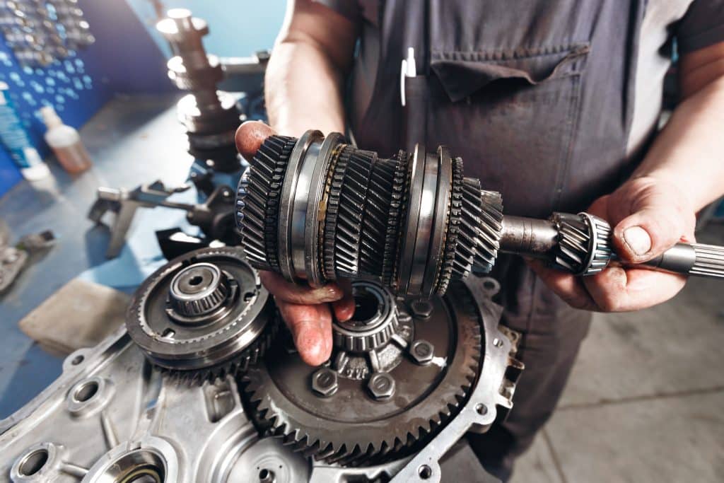 Close up of a mechanic's hands holding up a light commercial vehicle gearbox.